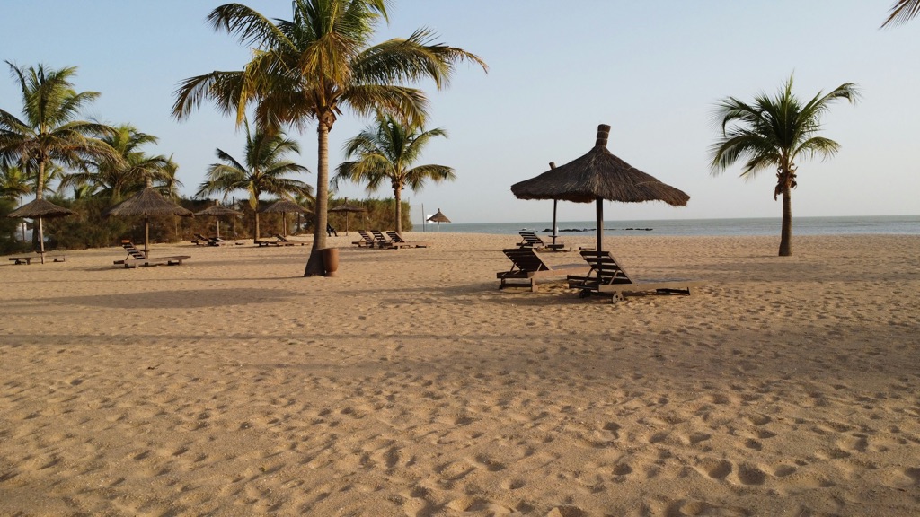 Stranden i Saly med palmer, stråparasoller og solsenger.